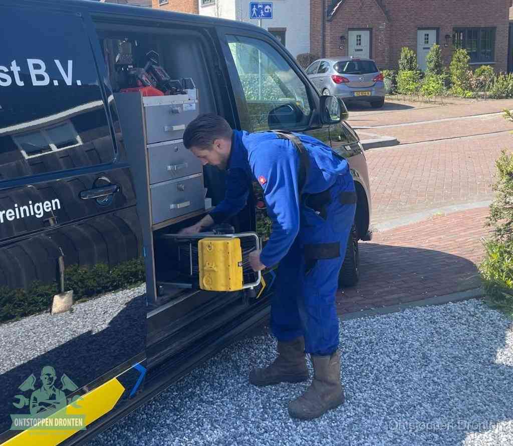 Een monteur pakt buiten op de oprit gereedschap uit de bedrijfsbus, het moment om een professional in te schakelen voor een verstopte afvoer in Dronten