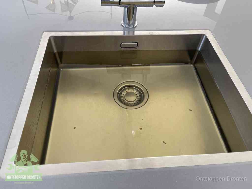 Stilstaand water in een rvs spoelbak dat niet wegloopt, een duidelijk signaal van een gootsteenverstopping in Dronten