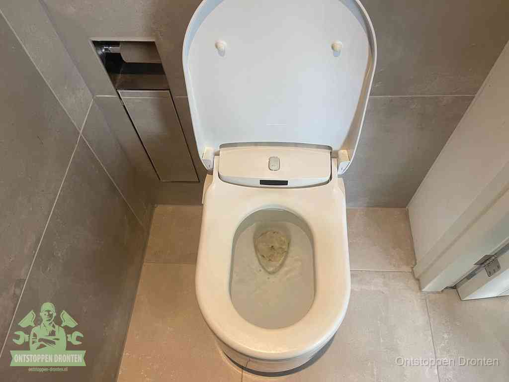Een wit hangtoilet waarin een prop wc-papier op het water blijft drijven, een duidelijk signaal van een verstopte wc in Dronten