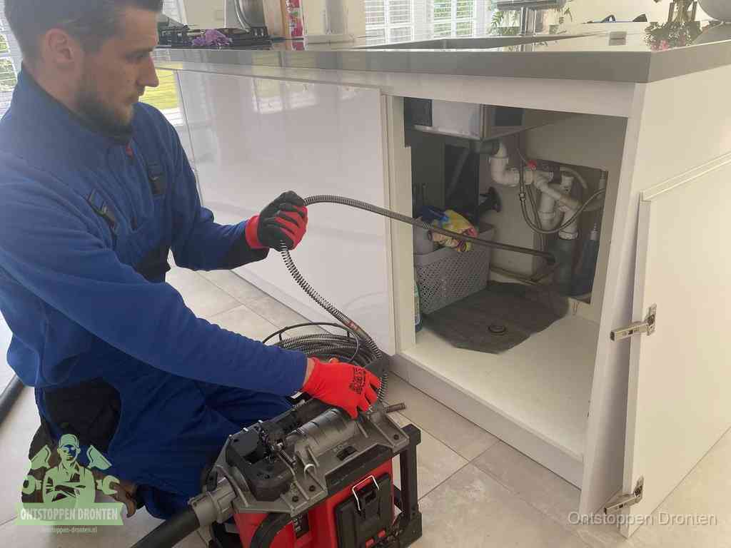 Een monteur reinigt de keukenafvoer grondig met een veermachine om terugkerende gootsteenverstoppingen te voorkomen in Dronten