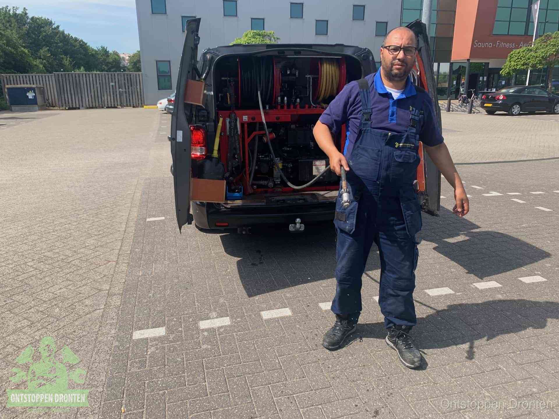 Een monteur bij zijn bestelbus met een hogedruk- en rioolreinigingsunit, klaar om de oorzaak van terugkerende wc-verstoppingen aan te pakken in Dronten
