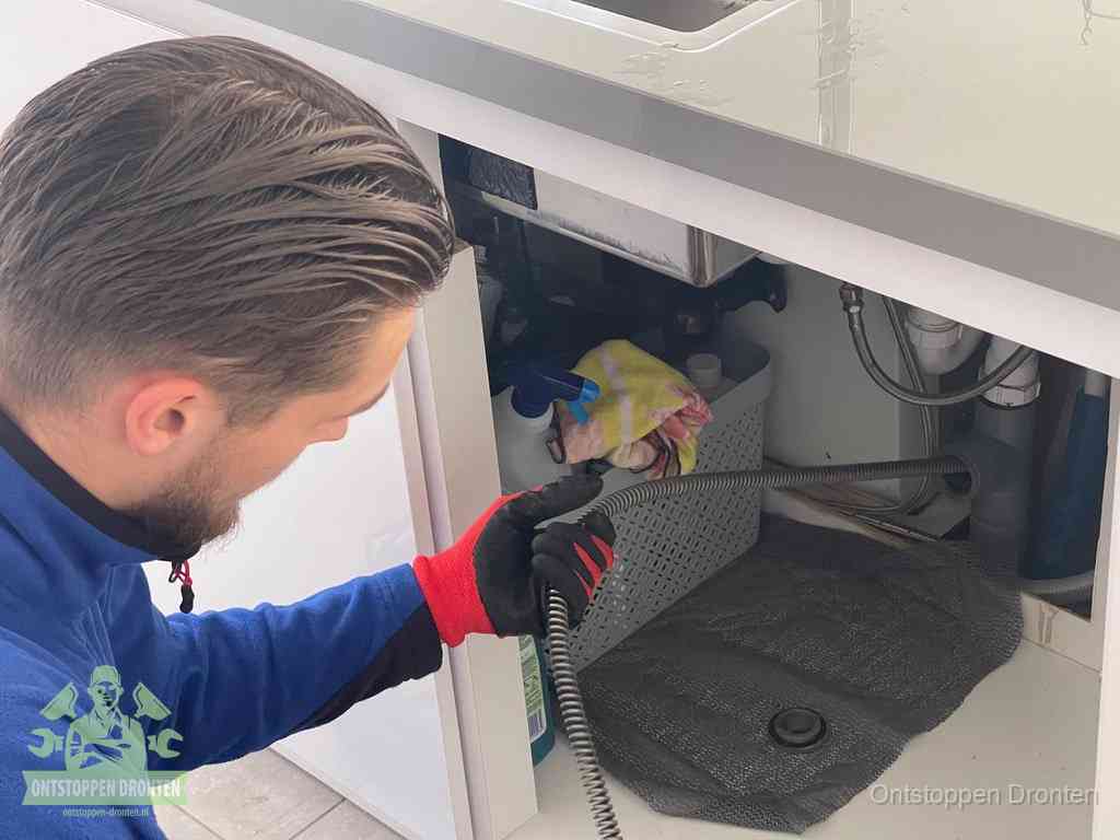 Een monteur voert een flexibele ontstoppingsveer in de afvoer om een verstopping voorbij de bocht van het toilet te bereiken in Dronten