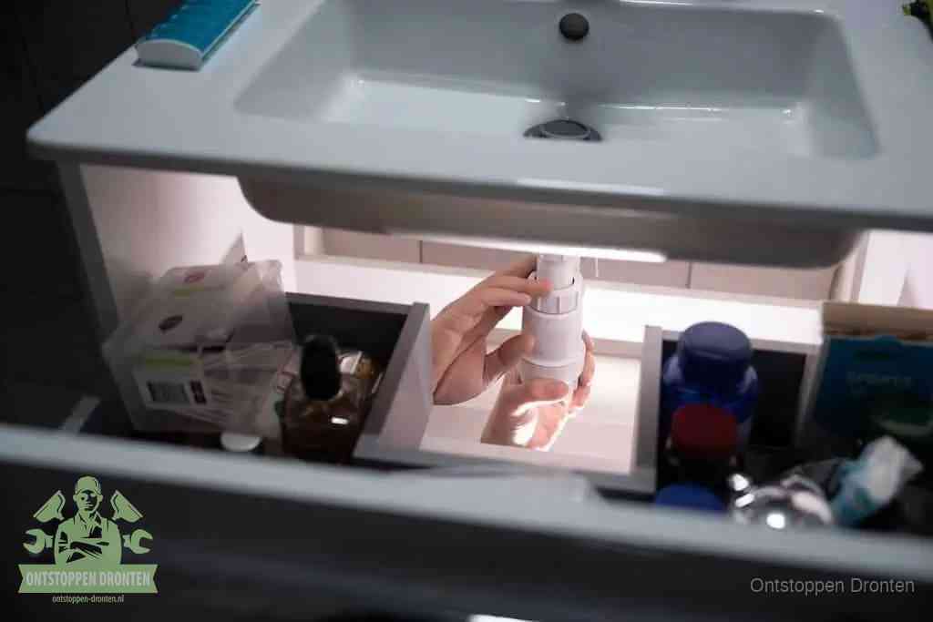 Een pompfles met zeep boven een wastafel in de toiletruimte, de warm water en afwasmiddel-methode om de wc te ontstoppen in Dronten
