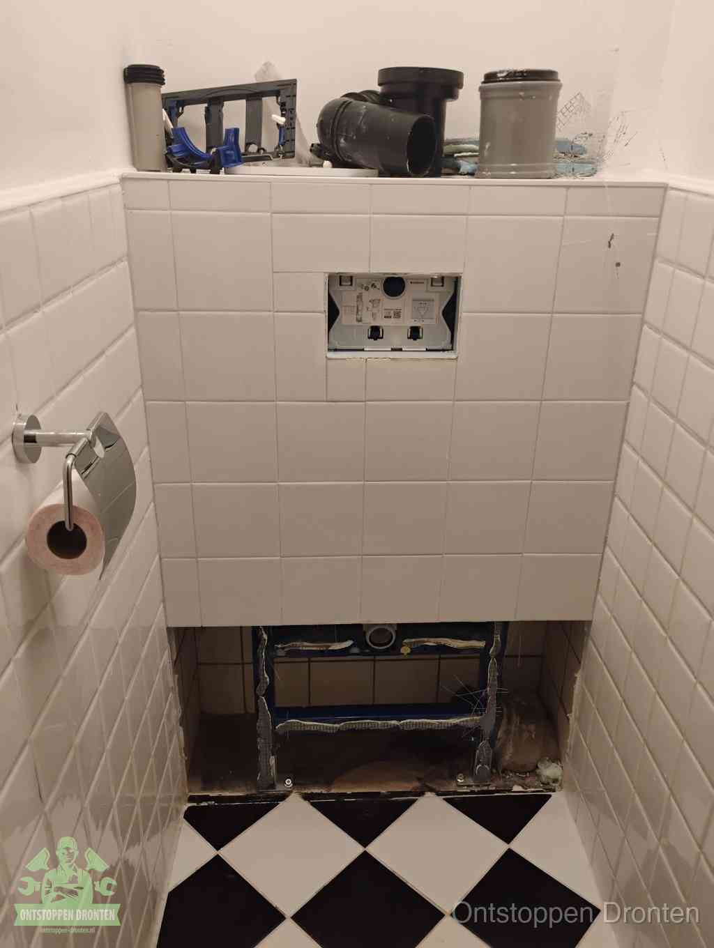 Een toiletruimte waar het hangtoilet en de inbouwreservoir-onderdelen zijn vrijgelegd voor onderhoud, periodiek nazicht voorkomt een wc-verstopping in Dronten